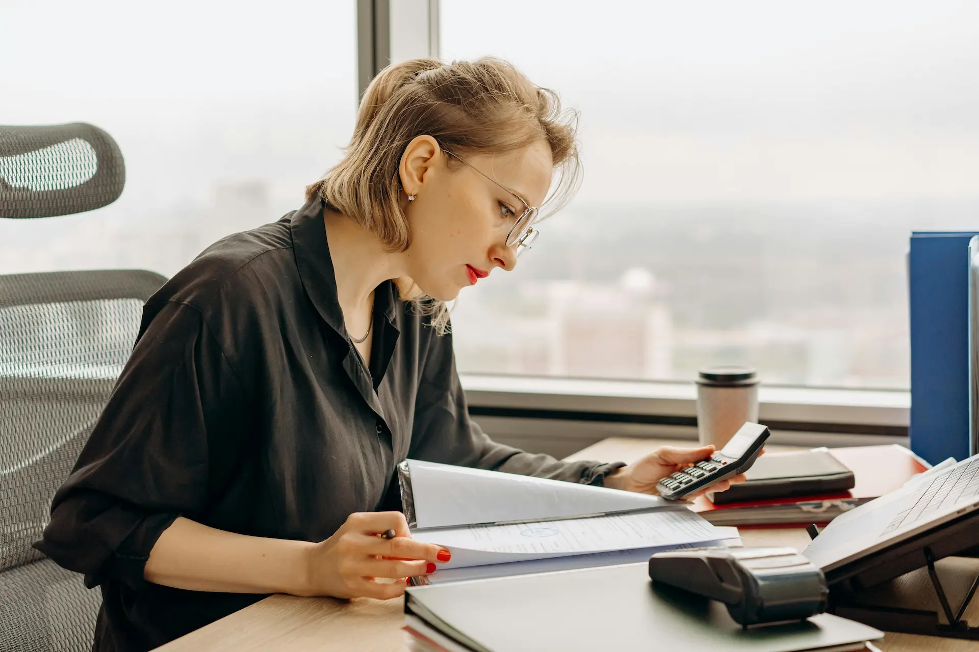 Étudiante ou professionnelle de la comptabilité analysant des documents financiers et utilisant une calculatrice à son bureau en formation BTS CG au Campus Saint Aubin La Salle