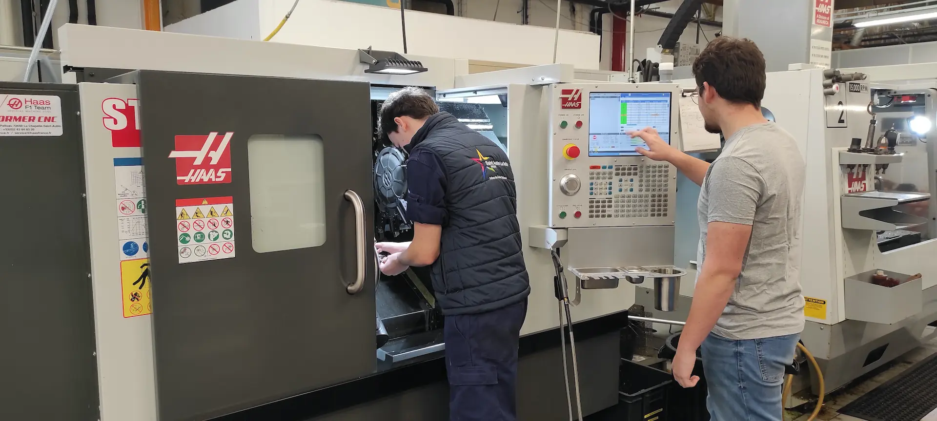 Deux étudiants manipulant et programmant une machine-outil à commande numérique Haas dans les ateliers du Campus Saint Aubin La Salle