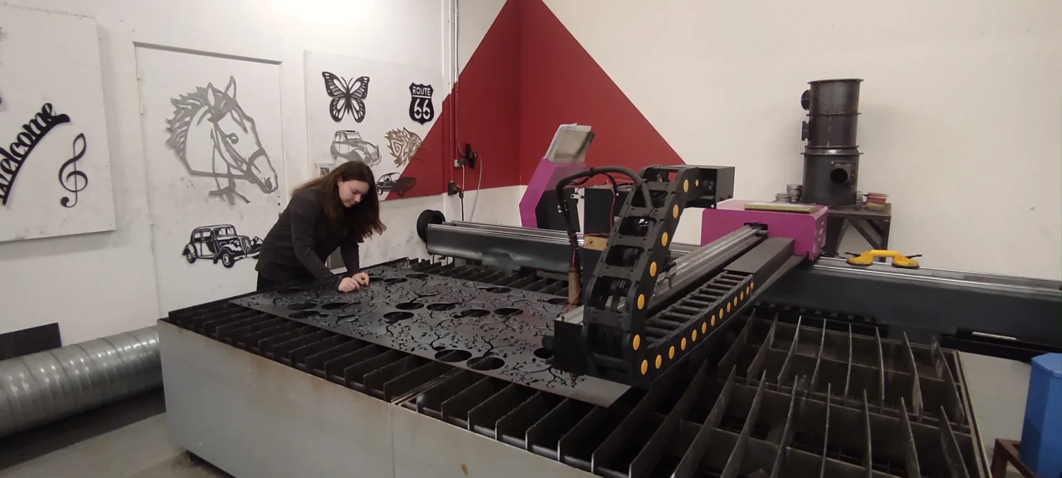 Étudiante préparant une plaque métallique sur une machine de découpe laser industrielle au Campus Saint Aubin La Salle